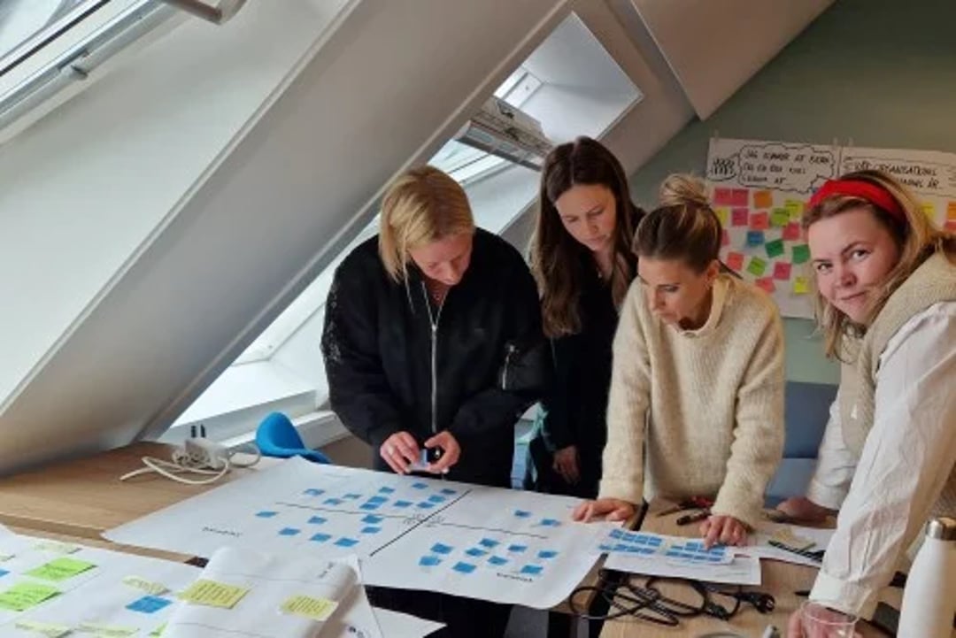 Astrid Levåg smiler til fotografen under gruppediskusjon med sine kollegaer.