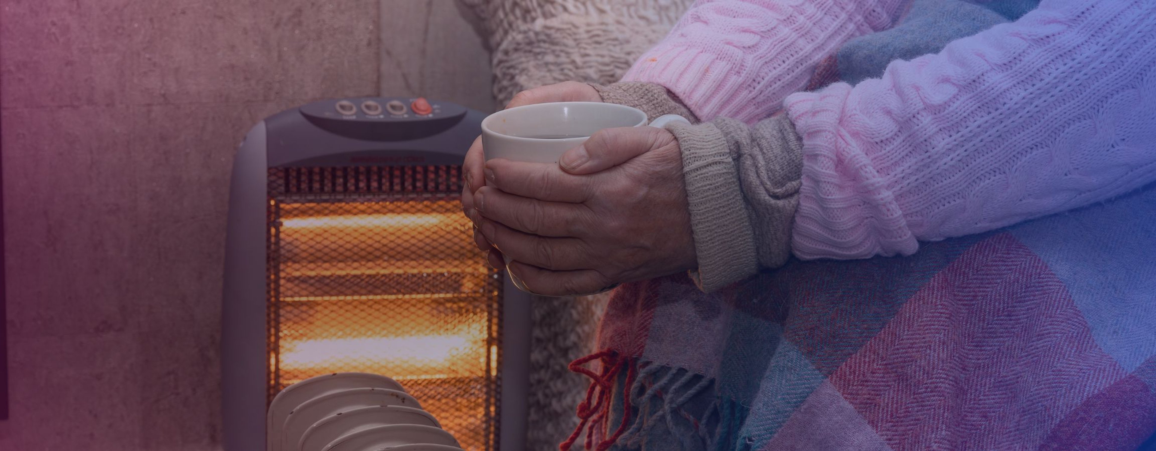An elderly person warming up their hands with a radiator