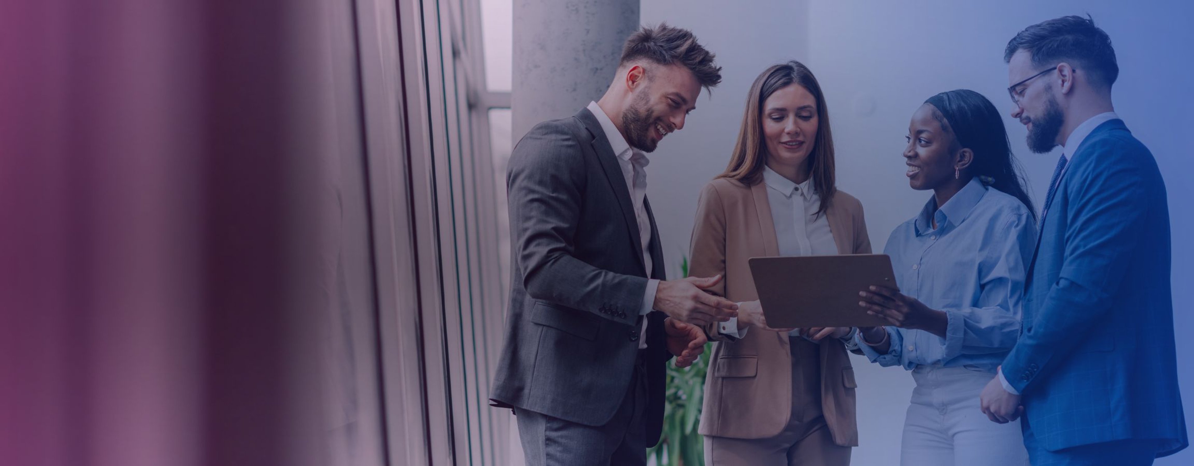 A group of employees looking at an electronic tablet in an office